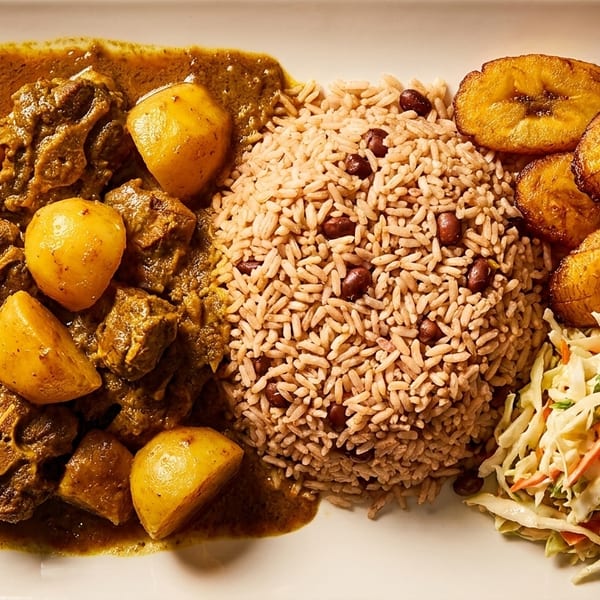 Oxtail stew with potatoes, rice and peas, fried plantains, and coleslaw on a white rectangular plate.
